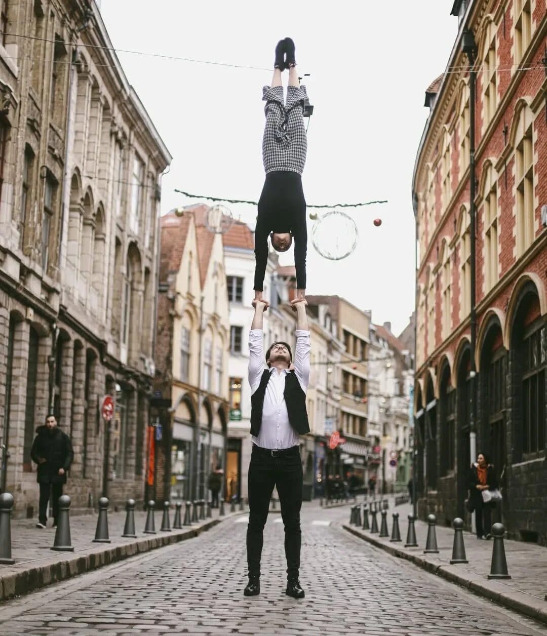 Hand to hand in a cobbled street, the flyer in a straight handstand